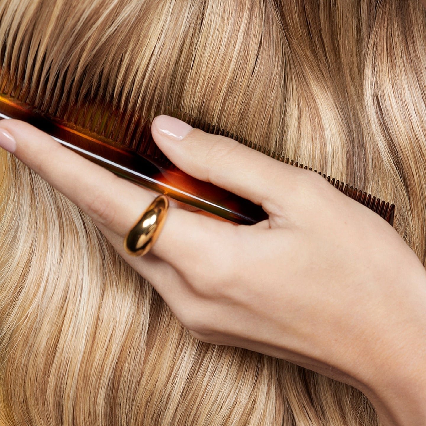 Eine Hand führt einen Kamm durch lange goldblonde Haare